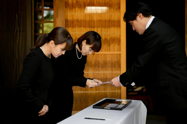 受付で香典袋を差し出す参列者