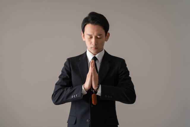 数珠を手に合掌する男性