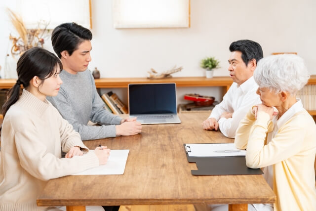 テーブルを囲んで話す4人