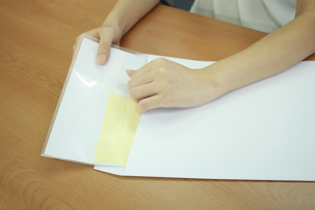 書類をクリアファイルに入れる手元